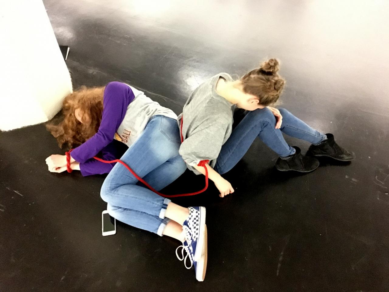 Two schoolgirls lie on the ground with a red rope as part of the »Art im Puls« event.