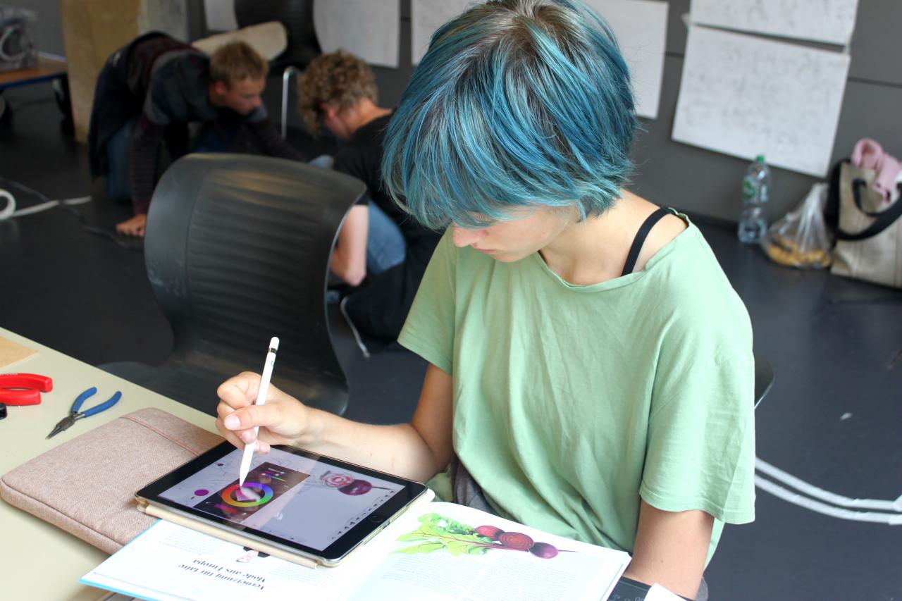 A schoolgirl is painting on an iPad as part of a cultural academy event.
