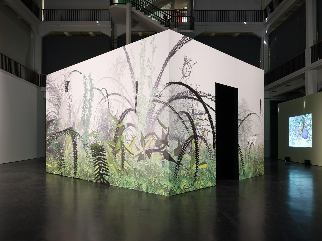 Zu sehen ist das Werk »Interactive Plant Growing«. Eine Aussenansicht zeigt das Werk von Außen. Ein Kubus, in dessen Inneren sich die Pflanzen befinden. Der Kubus ist von Außen mit floralem Muster geschmückt. Er steht mitten im Ausstellungsraum.