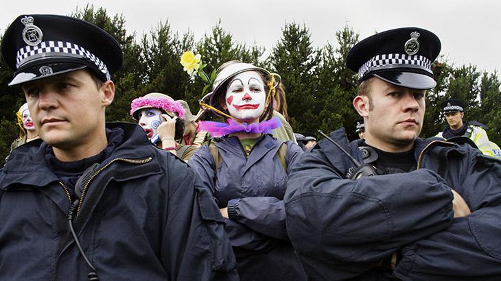 Two policemen are standing in front of a group of clowns