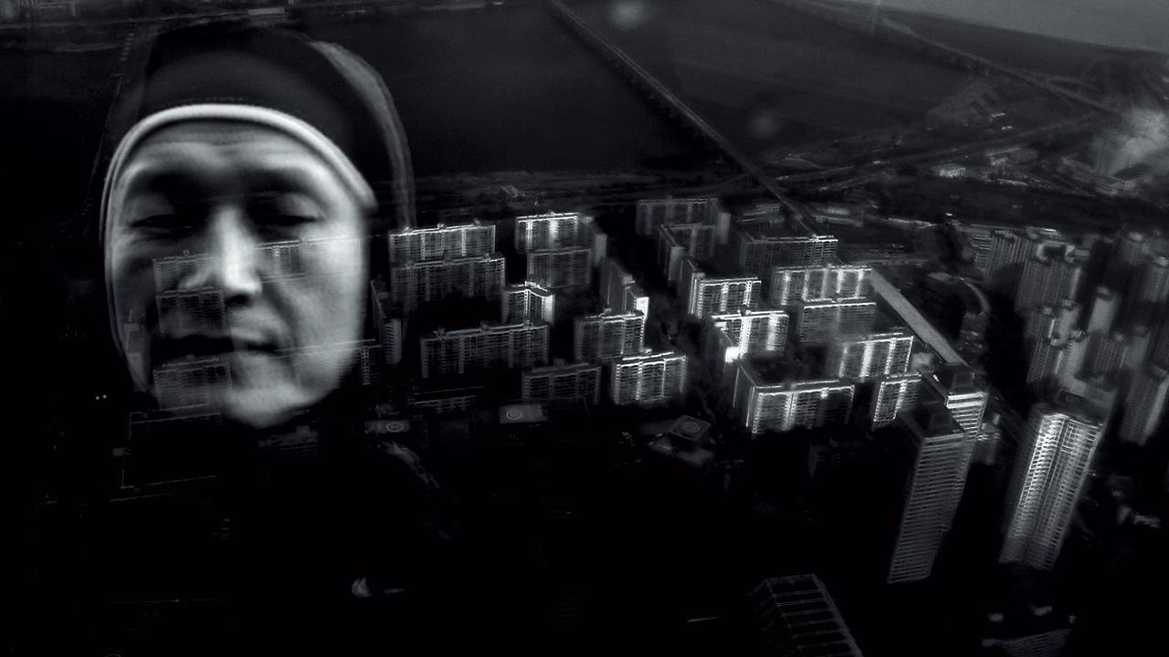 The black and white collage shows a nun in front of a bird's eye view on skyscrapers. 