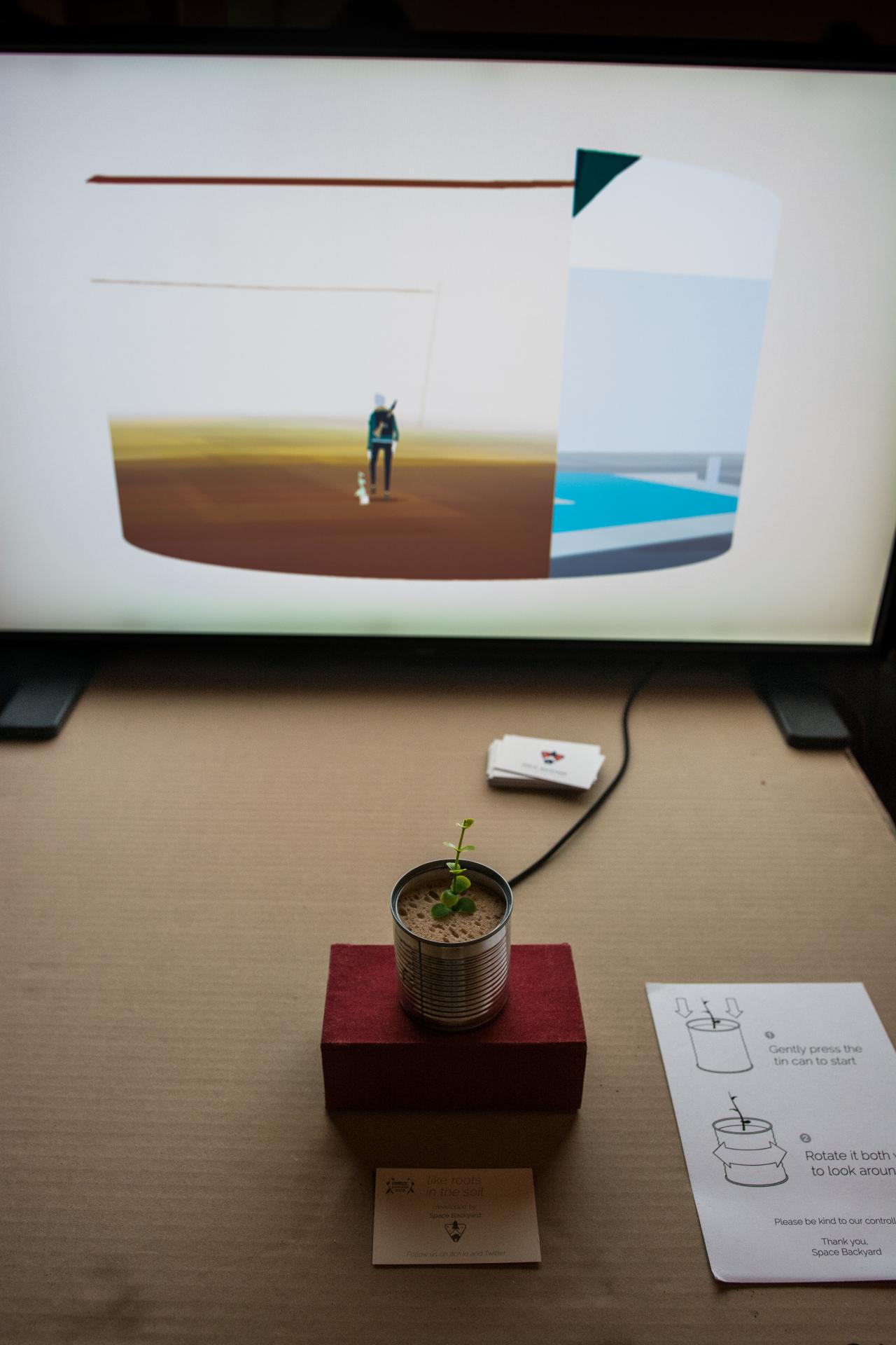 A plant grows out of a can that is connected to a screen.