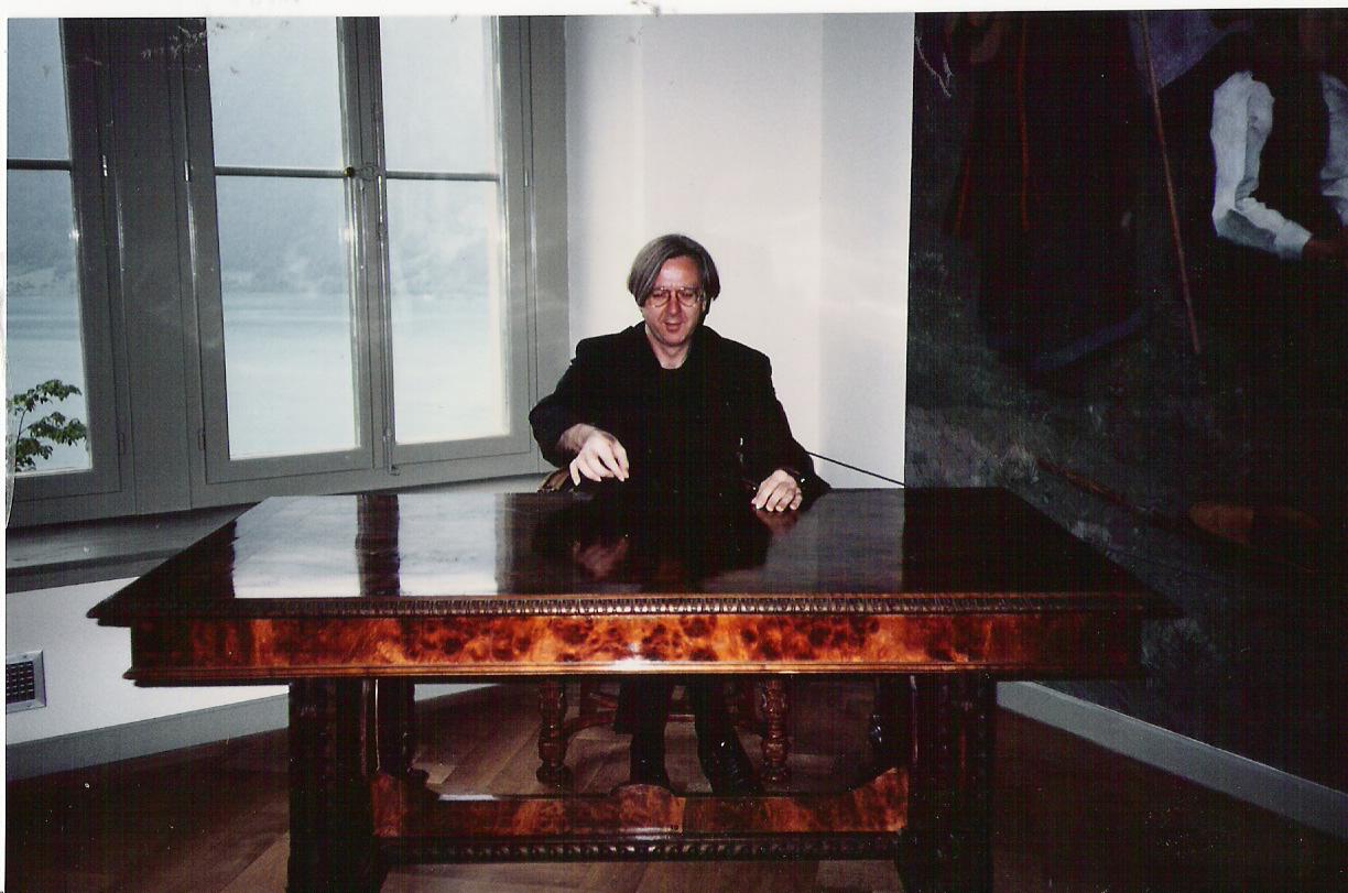 Fotografie von Gerhard Johann Lischka, hinter einem großen, schweren Schreibtisch sitzend