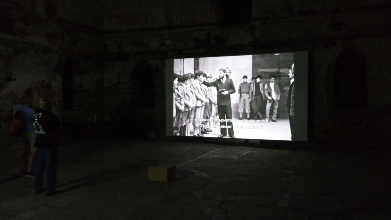 »After Pasolini – Visions of today« You can see a screen on which several people are shown.
