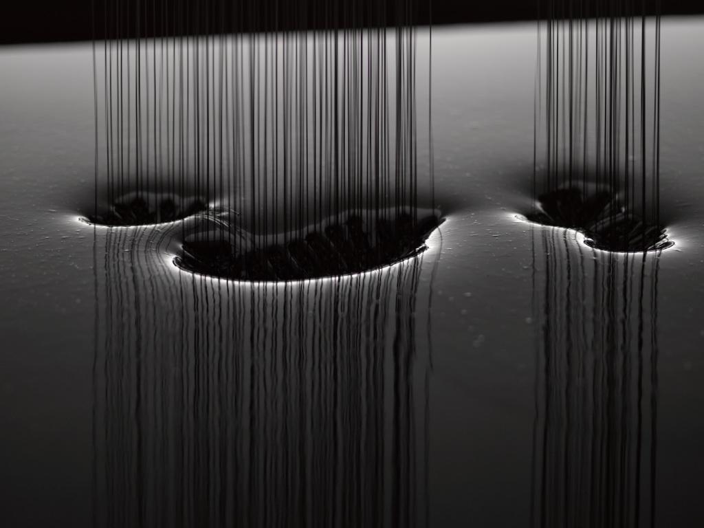 Black silicon oil drops into a bassin.