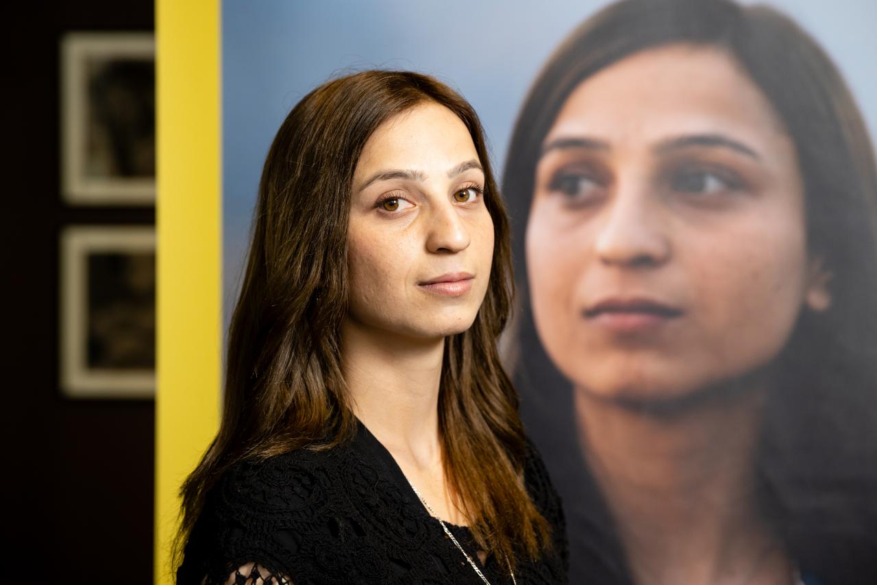 Yazidi activist Hala Safil is seen in front of the exhibition poster