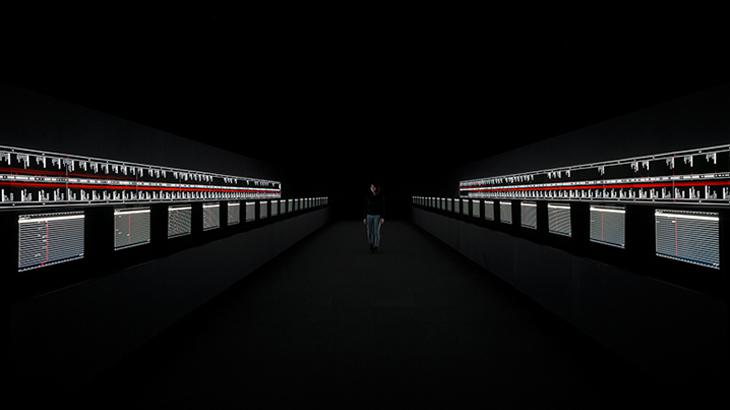 A person walks inbetween two rows of screens