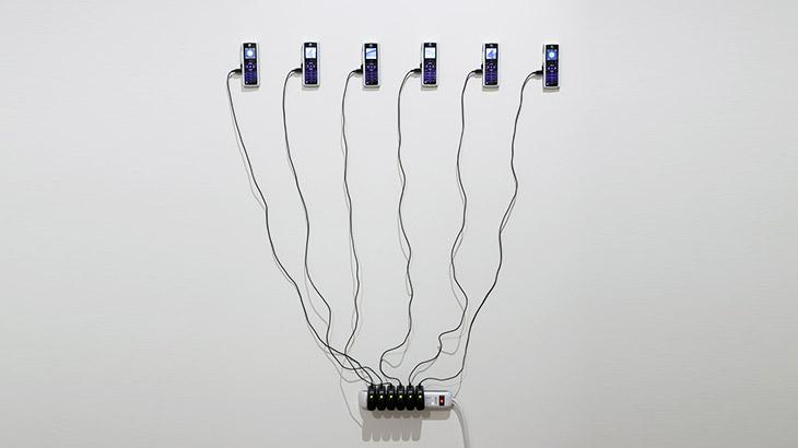 Installation on a wall out of six mobile devices connected to charger cables