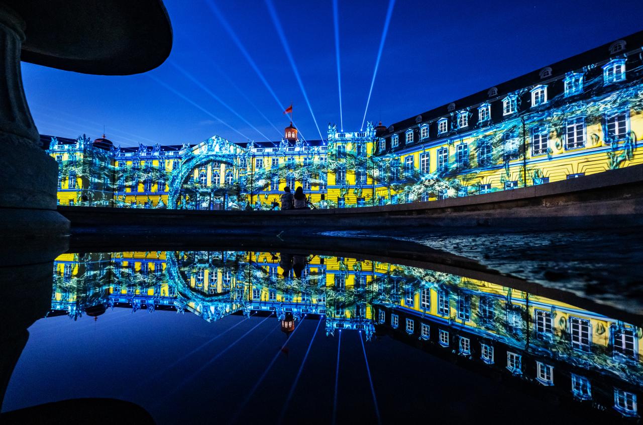You can see the illuminated facade of the Karlsruhe Baroque Palace in the colors blue and yellow.