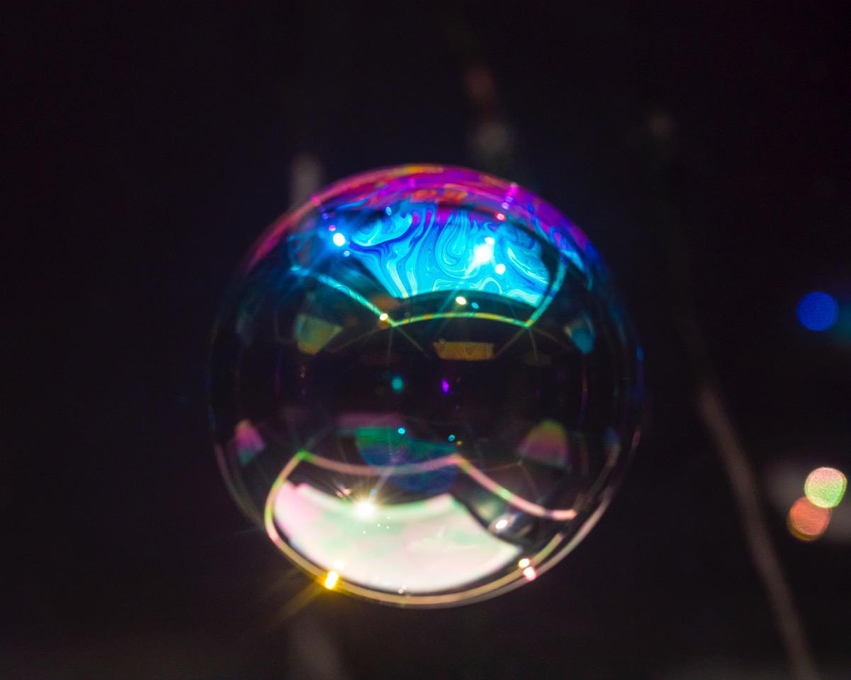 The photo shows a sphere similar to a huge soap bubble in front of a black background.