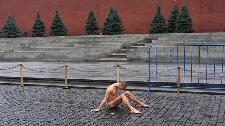 A naked man is sitting on the street