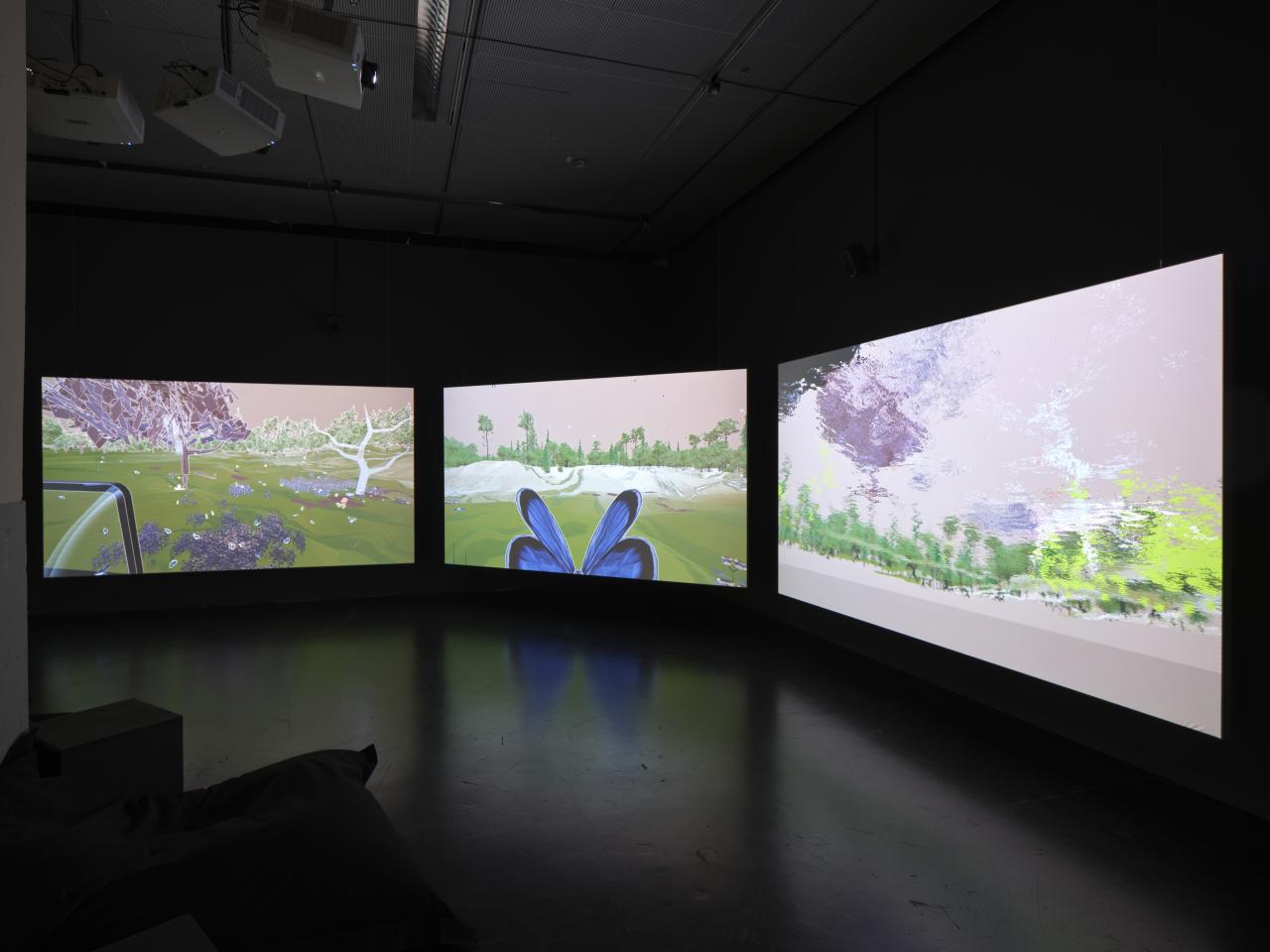 The picture shows a dark room with three large screens in the middle. The screens show a Ki-generated beautiful landscape with lots of green and a butterfly.