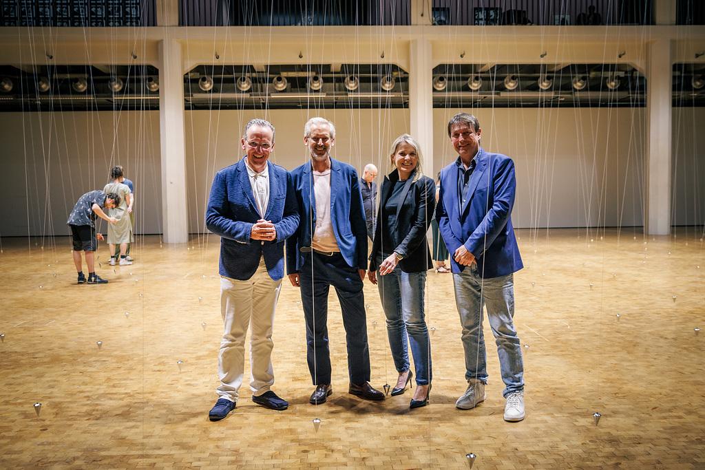 3 men, including the mayor of culture and the board of the ZKM, and a woman, the head of the cultural department of the city of Karlsruhe, stand in the atrium. William Forsythe's pendulums can be seen behind them.