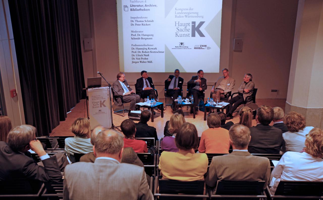 Besetzter ZKM_Vortragssaal mit Blick auf Teilnehmer der Podiumsdiskussion