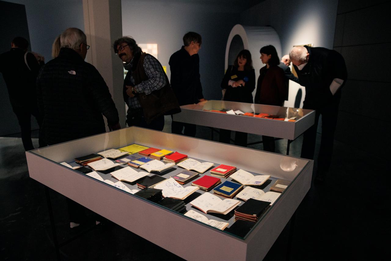 You can see several people gathered around two boxes. In the boxes are several books.