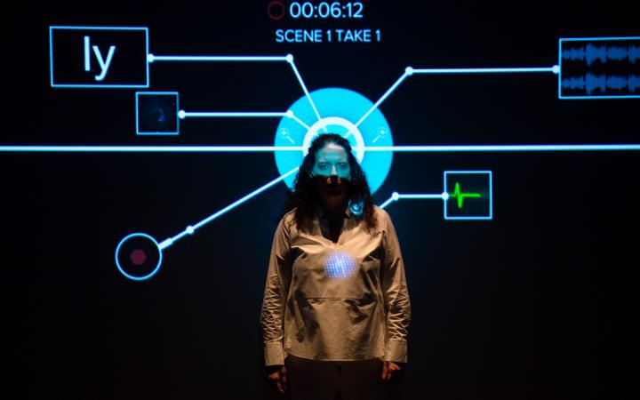 Noa Frenkel is standing in front of a projection. Her head is exactly in front of a circle and from this circle a mapping flows out in all directions.