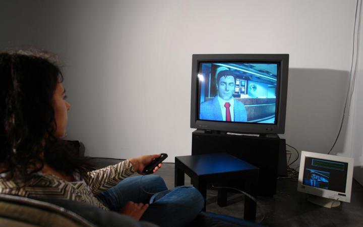 A woman sitting in front of a television with a remote control