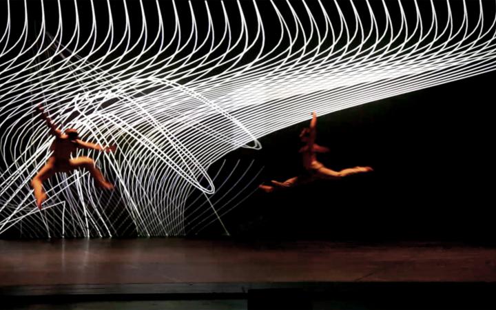 A stage. Two dancers move through the air. In the background spirally white structure.