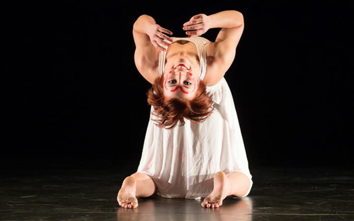 A woman knies down and bends over backwards
