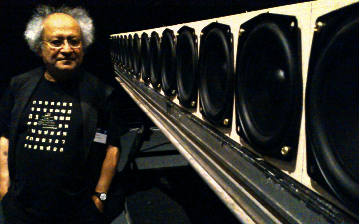 A man stands next to a set of speakers