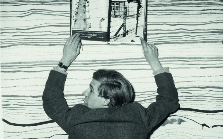 Schwarz-weiß Bild von einem Mann der ein Buch hochhält