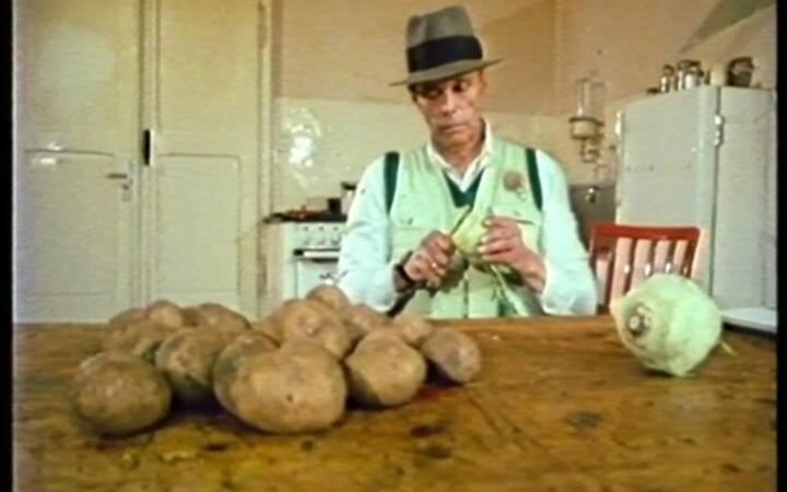 A man sitting at a table and peels potatoes and turnips