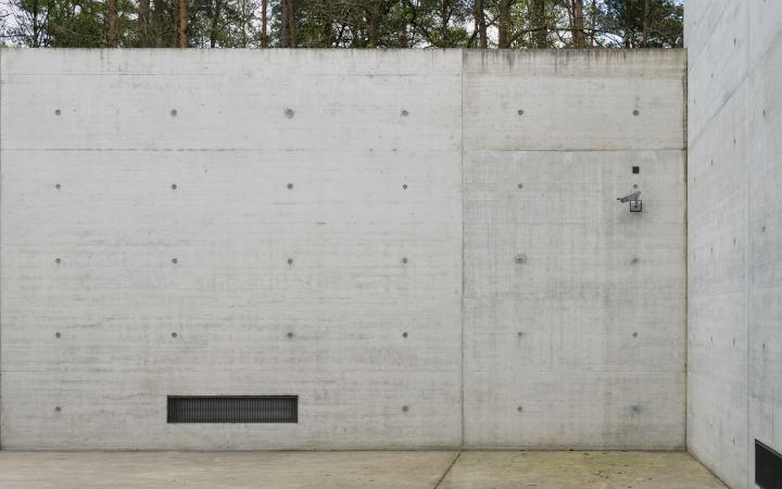  concrete wall with a vent on the left and a surveillance camera above right