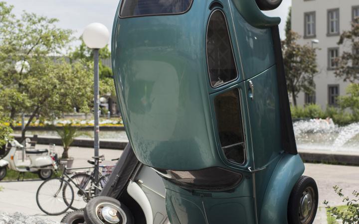 A green VW beetle standing on its head
