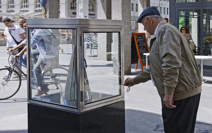 A man takes a silver megaphone from a glass cabinet