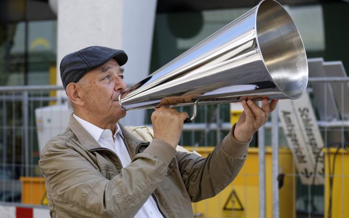 A man stands on the street with a silver megaphone