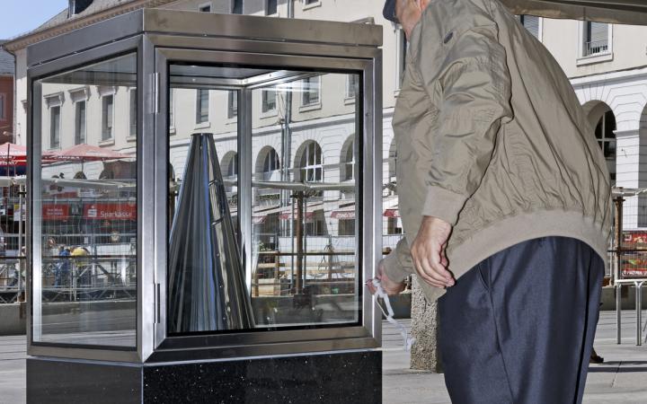 Ein Mann stellt ein silbernes Megafon zurück in eine Glasvitrine