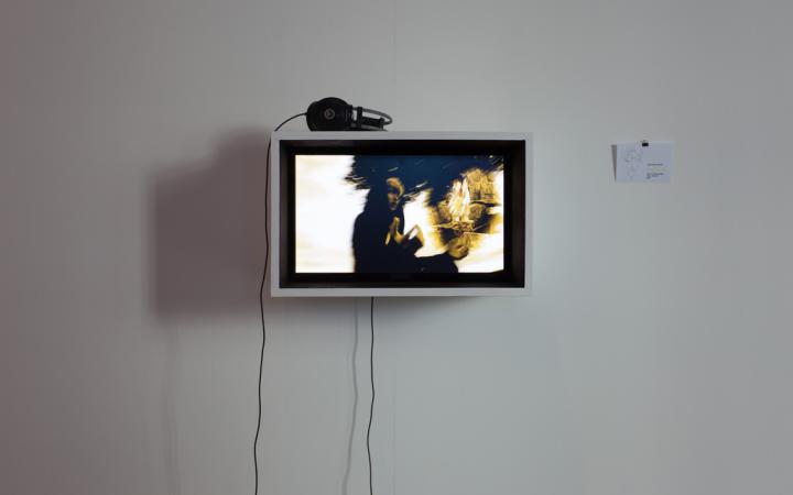  An der Wand hängt ein Monitor, auf dem ein Film läuft