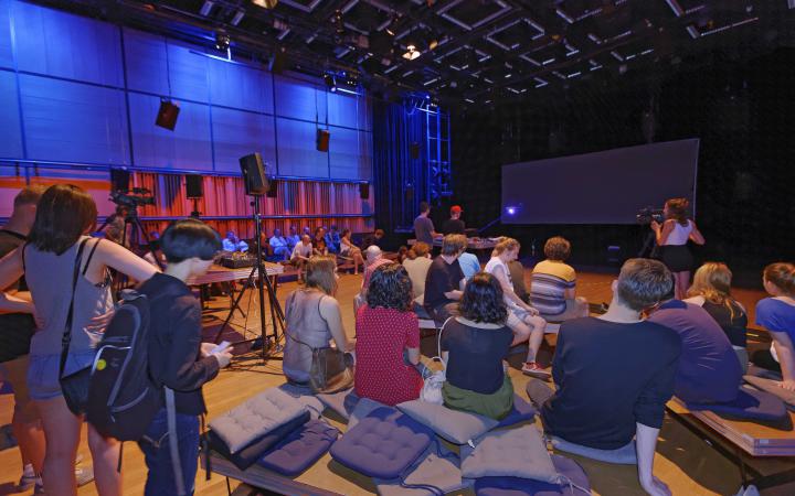 People sitting on the ground in front of a stage
