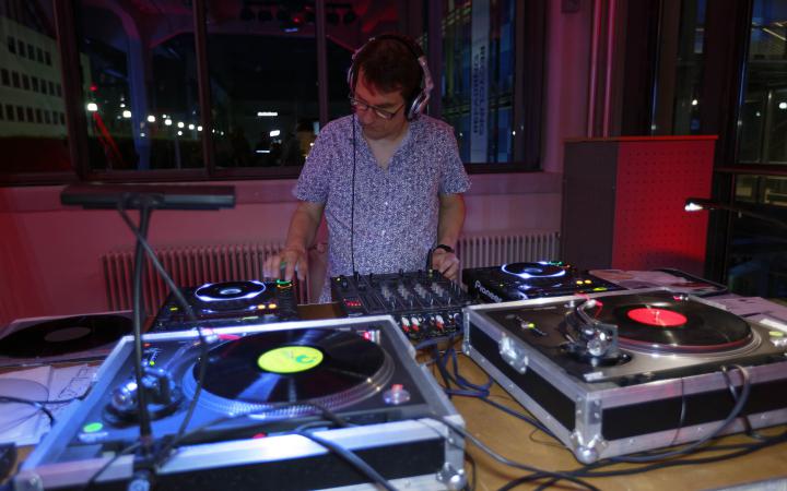 A man with microphones in front of a DJ set