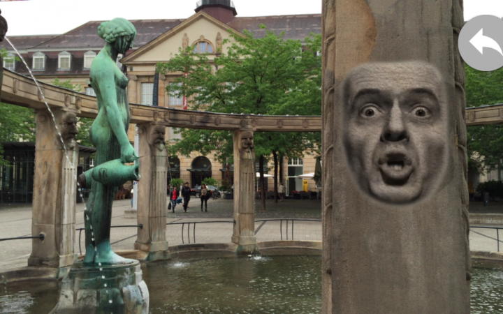View of the fountain at Stefansplatz: on the column the projection of a speaking, male face.