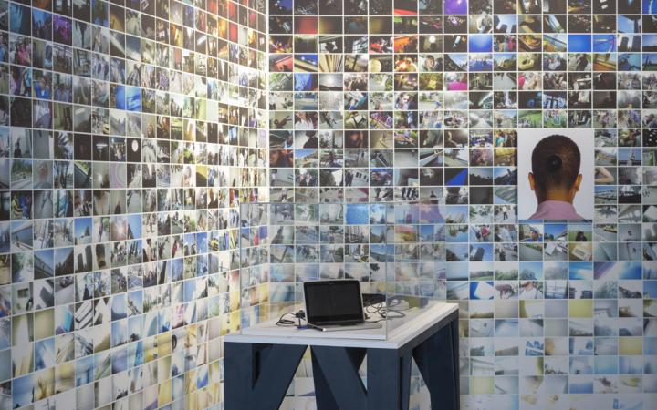 A rear wall with many small photos. In the foreground: A laptop on a table