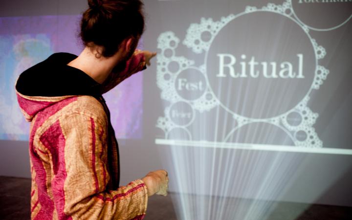 Eine Person vor einer Projektion, auf der "Ritual" steht