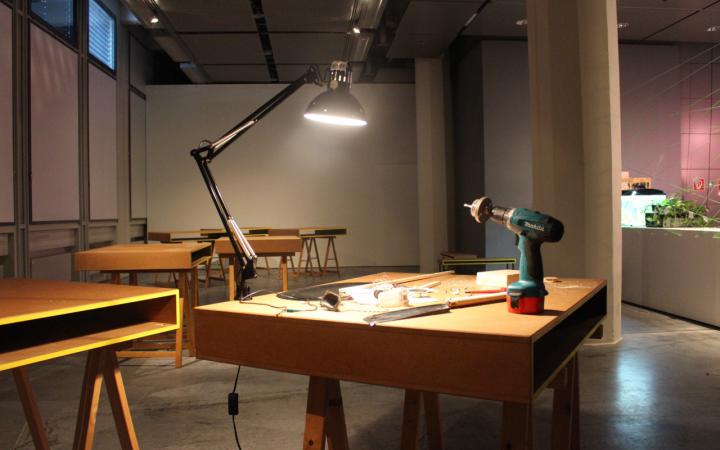A wooden table on which a lamp and a drill stands