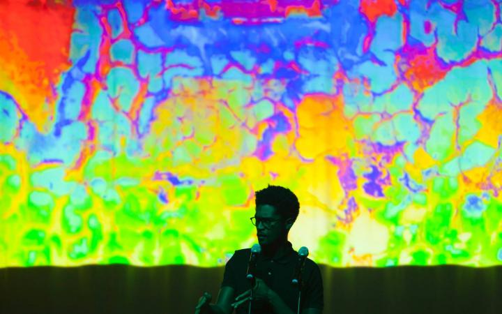 A man stands in front of a colorful screen
