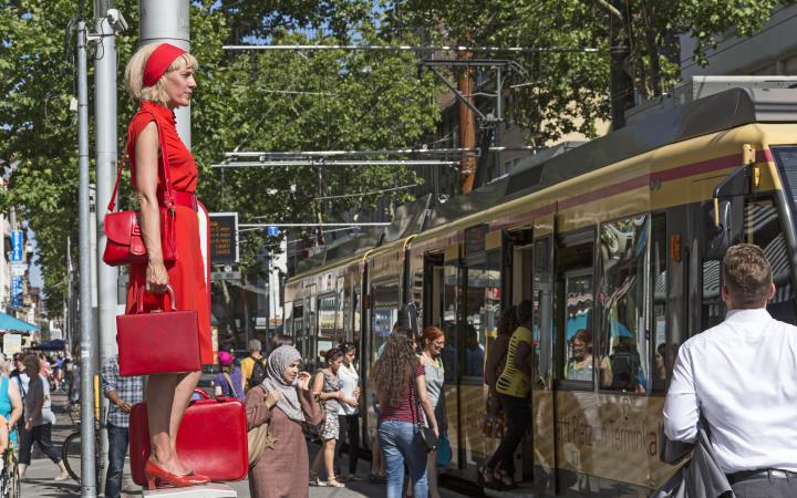A woman in red is standing on a power box in the middle of the pedestrian zone