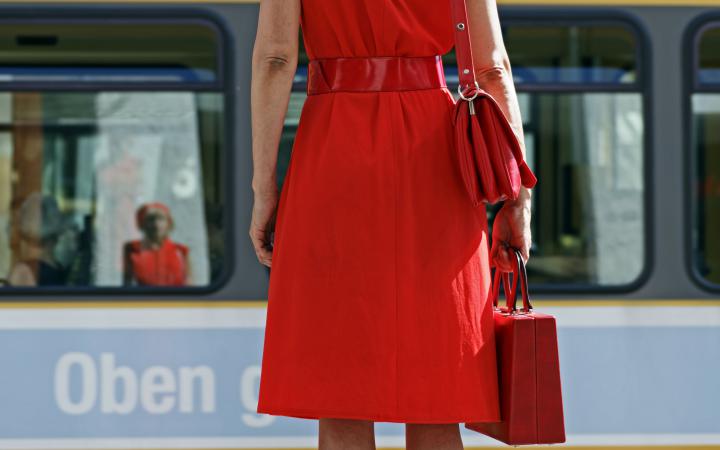 A woman in red is standing on a power box in the middle of the pedestrian zone