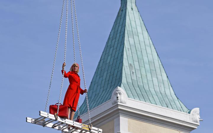 Eine blonde Frau in rotem Kleid auf einer schwebenden Treppe