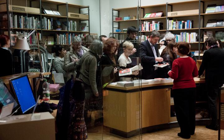 People stand in front of a desk full of books