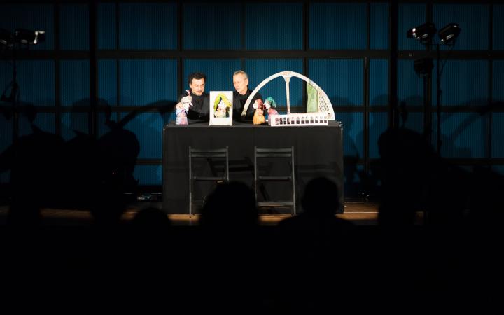 Two men play puppet theater