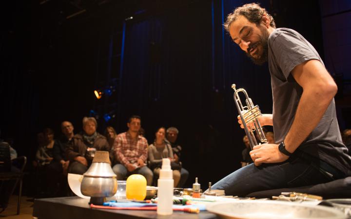 A man sits on the ground and presents different instruments