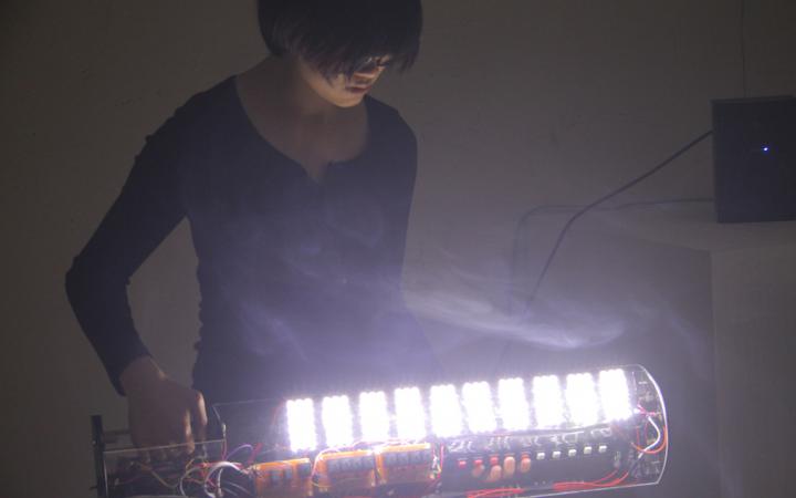 Eine Frau an einem selbstgebauten, leuchtenden Instrument
