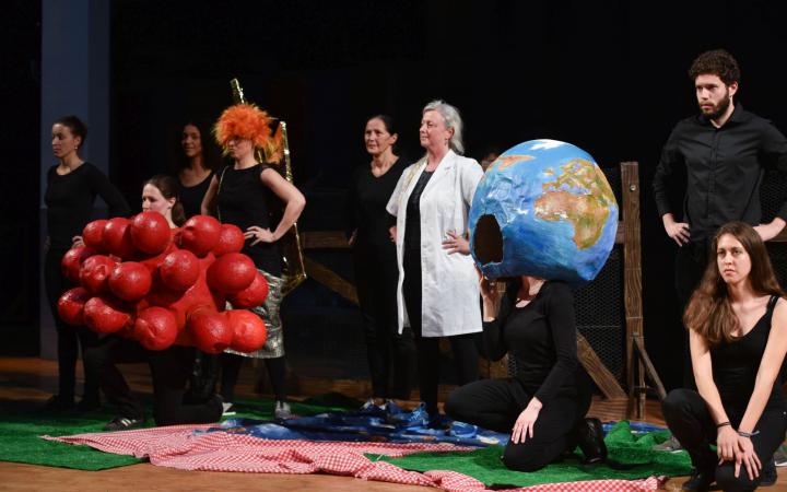 Several people standing in a row. In between a globe and molecules made of paper mache