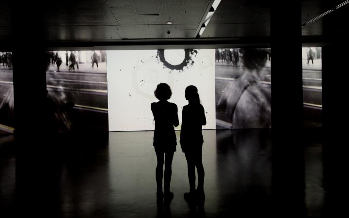 Zwei Besucherinnen vor einer Tambellini Video-Leinwand 