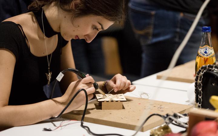 A woman is soldering a wire.