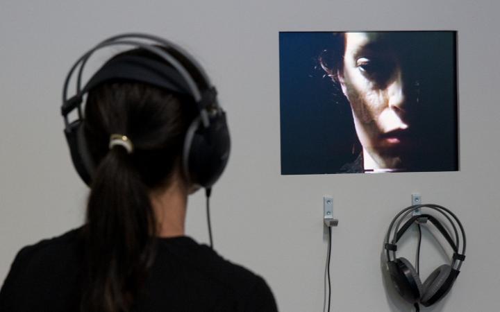 A woman with headphones is watching a video of another woman.